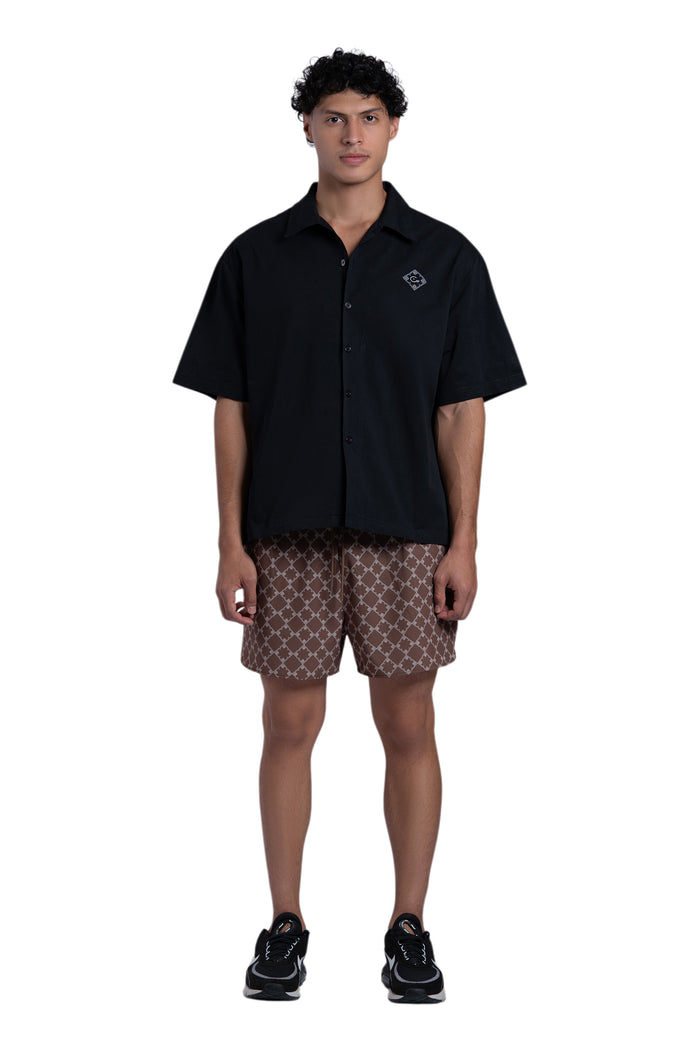 Person wearing a black polo shirt and patterned shorts on a white background